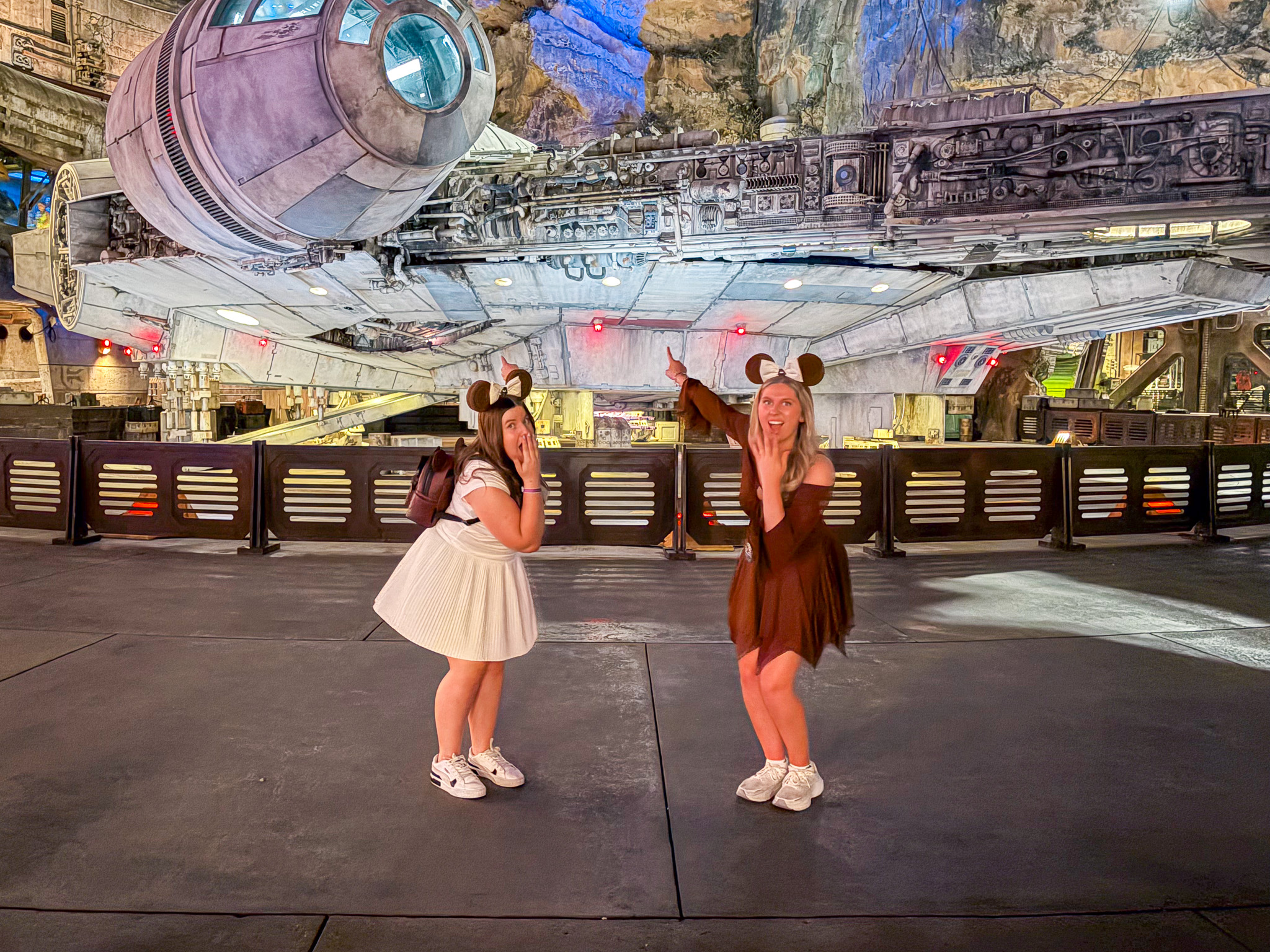 Star Wars: Galaxy's Edge at Hollywood Studios at night with colorful lightsabers illuminating the crowd in front of the Millennium Falcon.