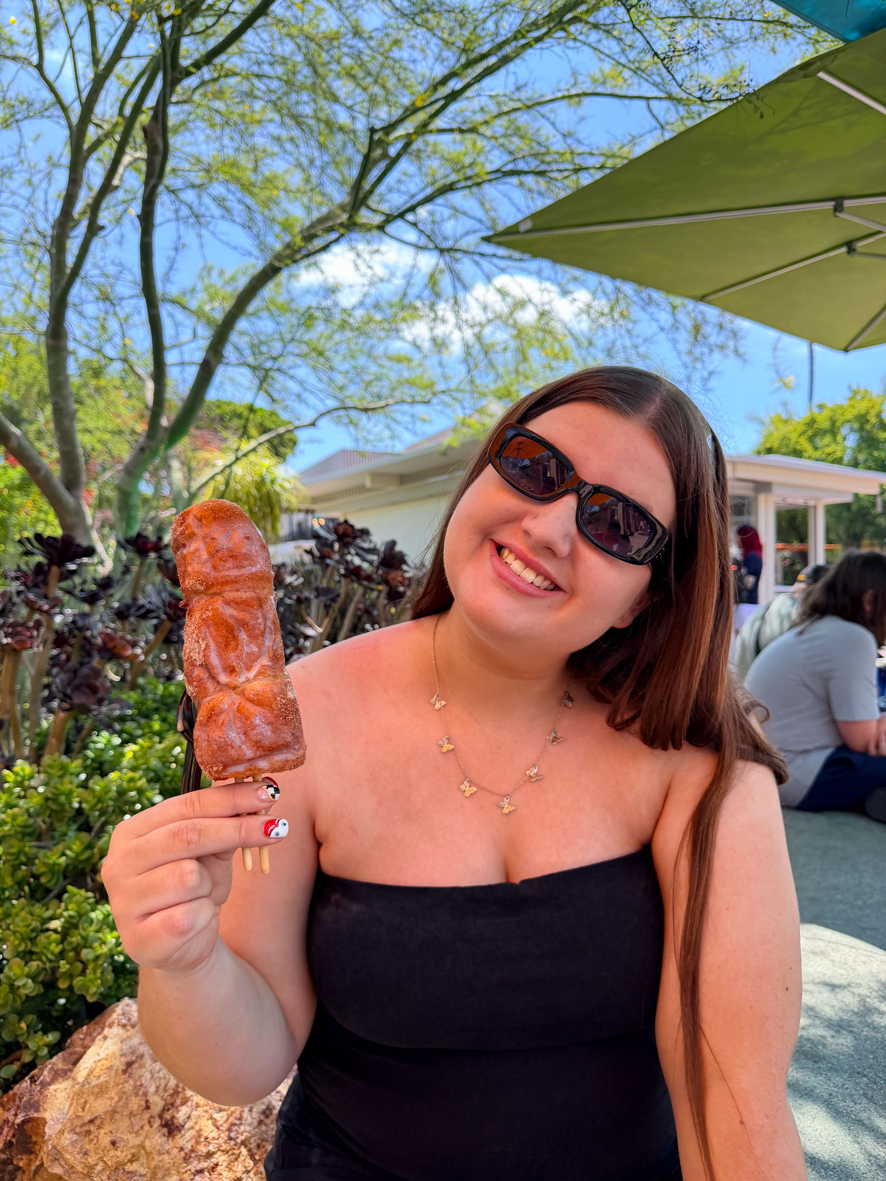 A teenage guest smiles while holding up a churro at Disney Springs.