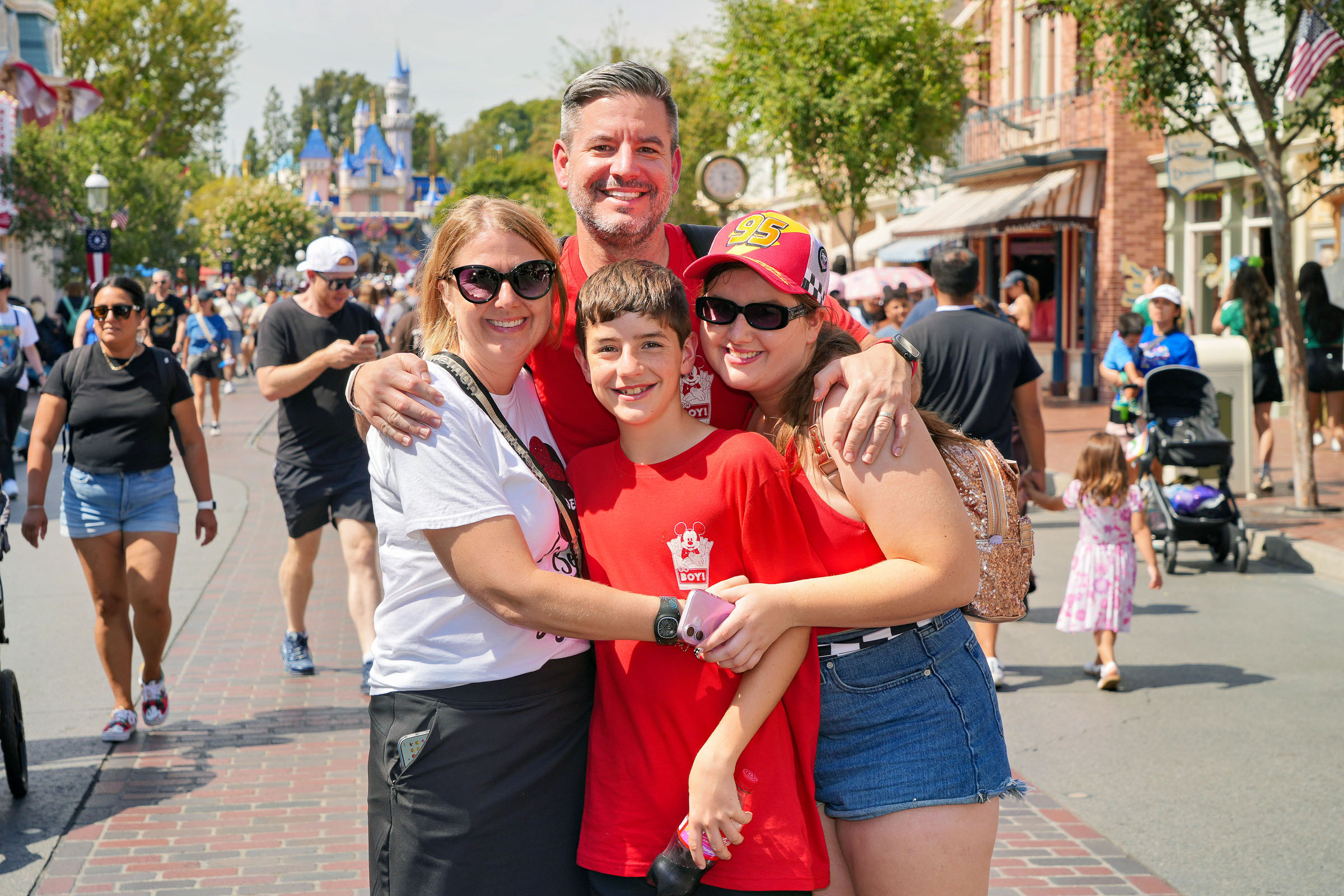 A family poses together on Main Street, U.S.A. at Disneyland with Sleeping Beauty Castle behind them.