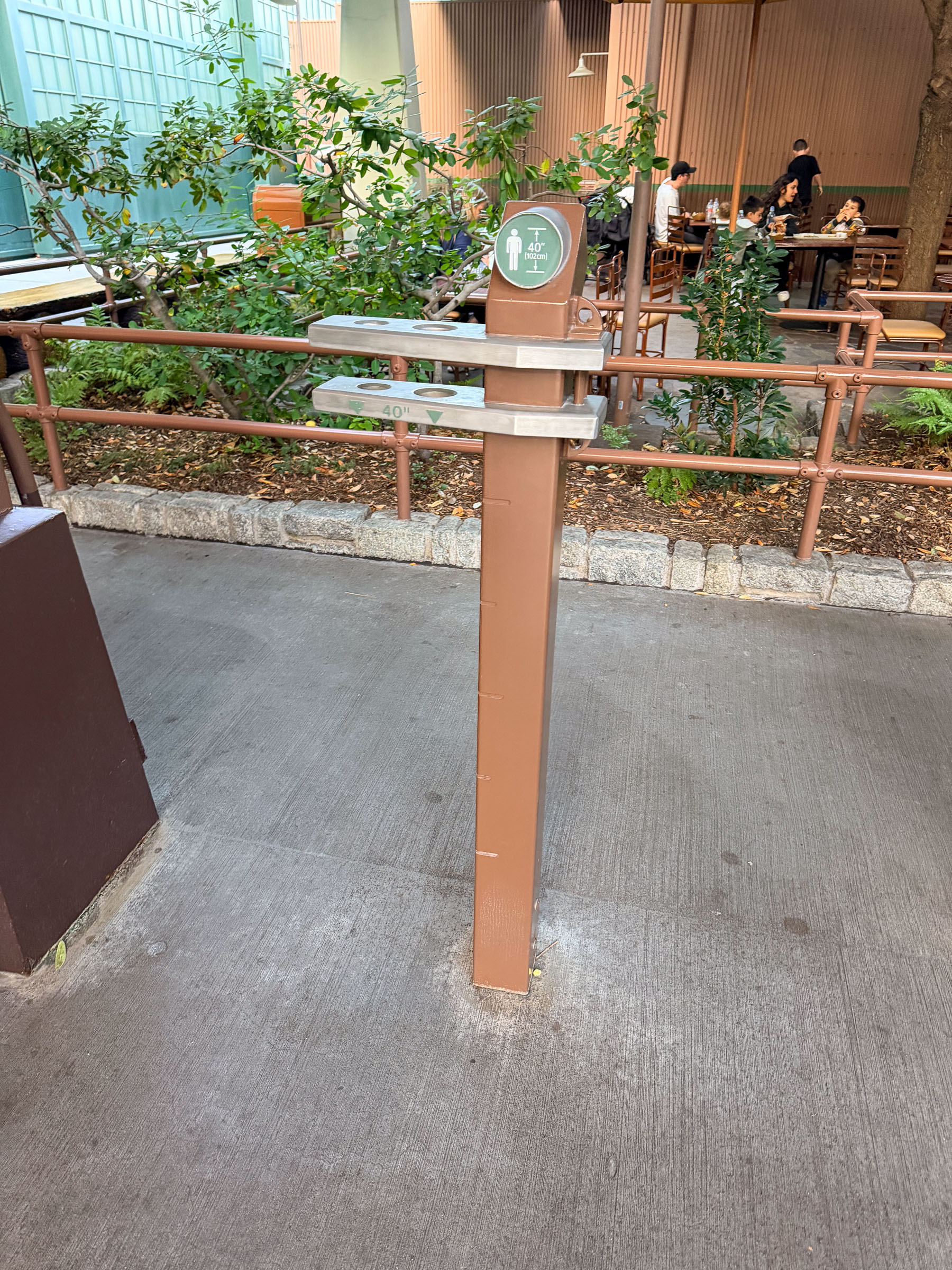 A 40-inch height-check post stands empty at a Disney theme park ride entrance.