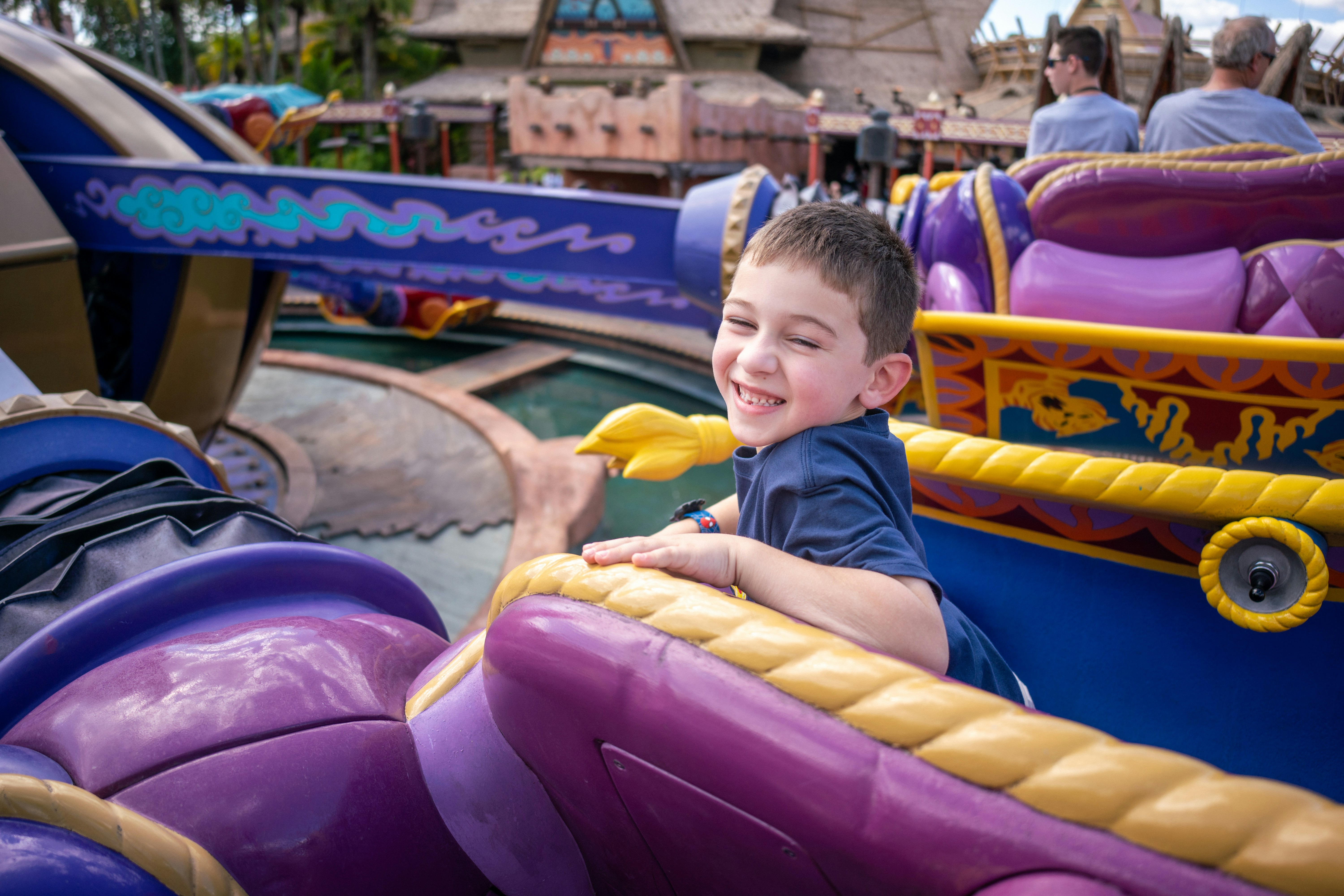 Young boy smiling while riding the Magic Carpet attraction at Walt Disney World.