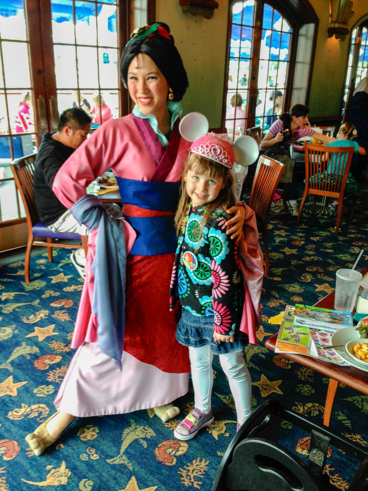 Very young girl in Snow White costume meeting Cinderella at a Walt Disney World princess experience.
