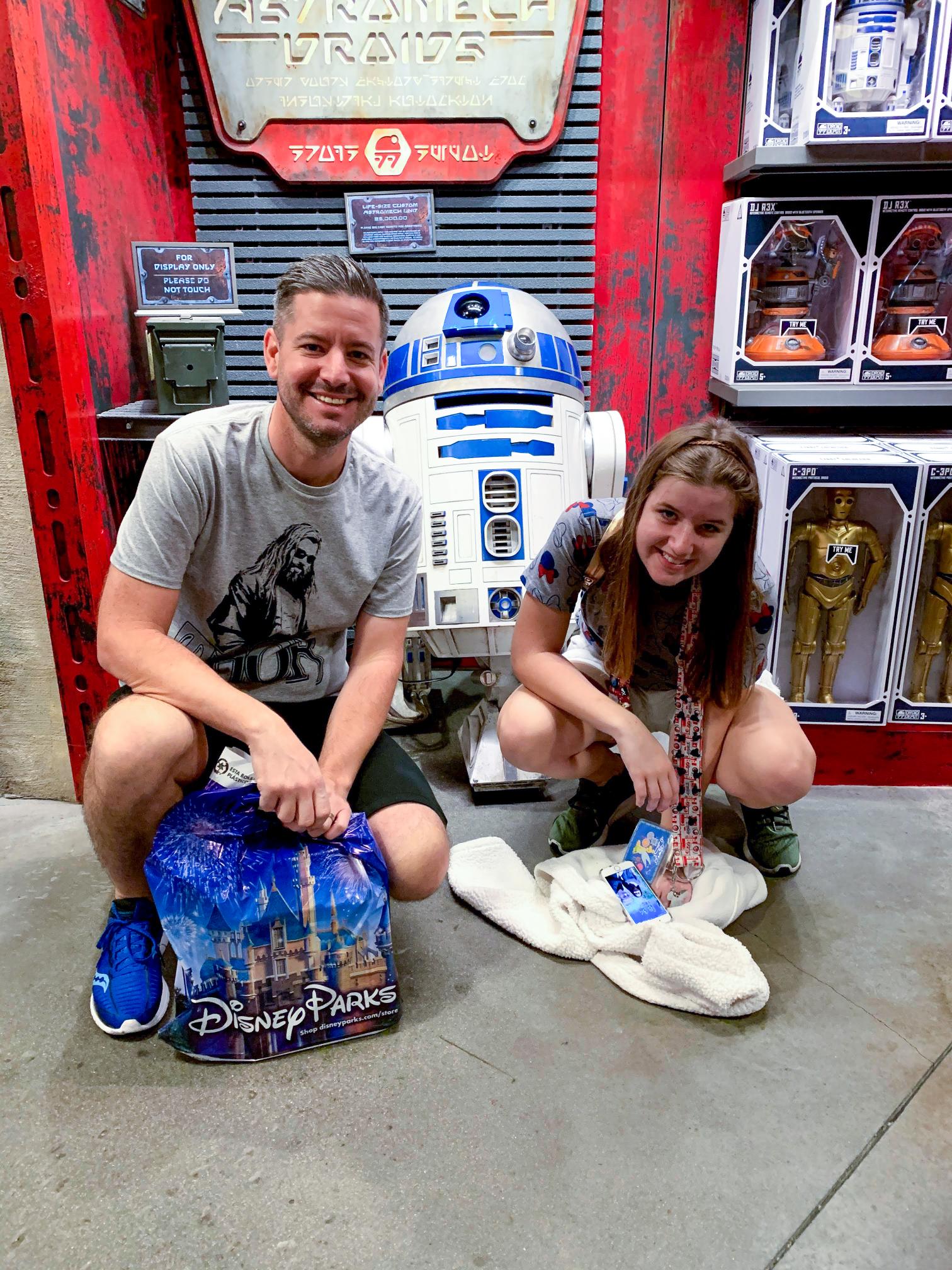 Father and teenager posing with R2-D2 at the Droid Depot in Star Wars: Galaxy's Edge at Disneyland.